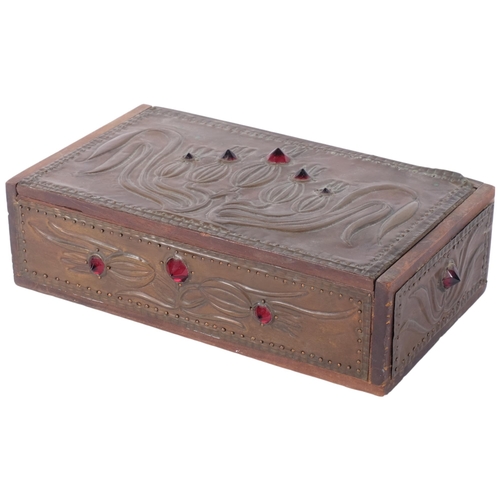 226 - An Art Nouveau rectangular box with embossed stylised copper clad panels and red glass bosses. Hinge... 