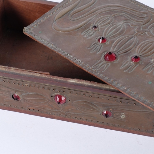 226 - An Art Nouveau rectangular box with embossed stylised copper clad panels and red glass bosses. Hinge... 