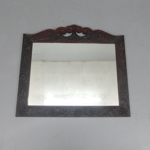 2253 - An Arts & Crafts wall mirror, with all-over applied carved foliate decoration. 105x95cm.