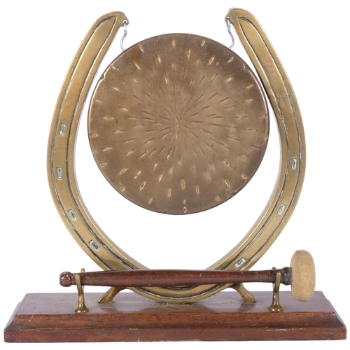 389 - A brass gong in horseshoe design stand, on oak plinth, with striker, H27cm