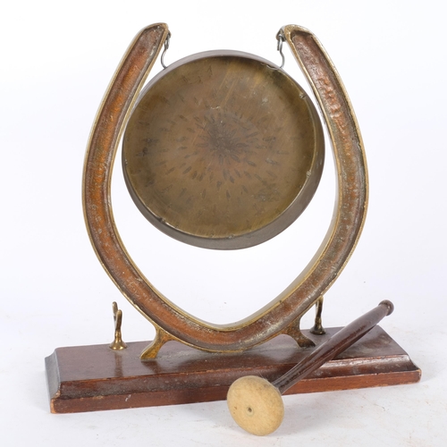 389 - A brass gong in horseshoe design stand, on oak plinth, with striker, H27cm