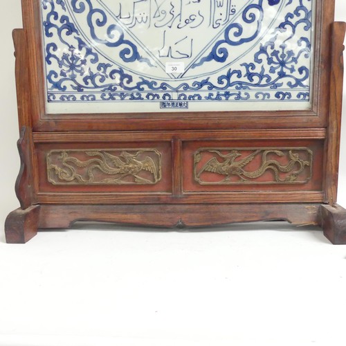 30 - A large middle eastern blue and white ceramic tile, with a scripted cartouche, mounted in a hardwood... 