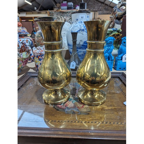 407 - A pair of heavy brass vases on feet, 25.5cm