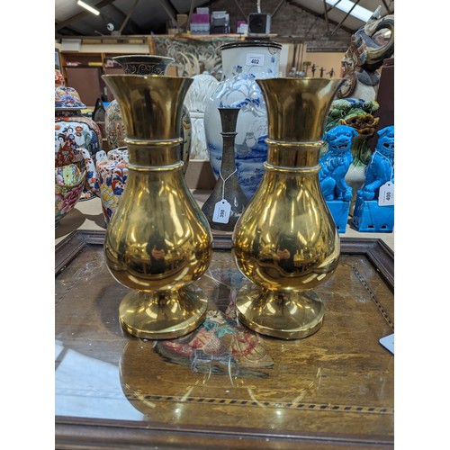 407 - A pair of heavy brass vases on feet, 25.5cm