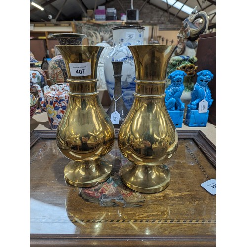 407 - A pair of heavy brass vases on feet, 25.5cm