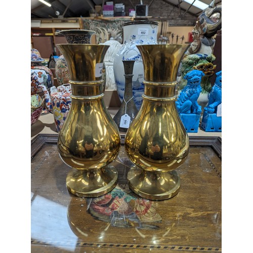 407 - A pair of heavy brass vases on feet, 25.5cm