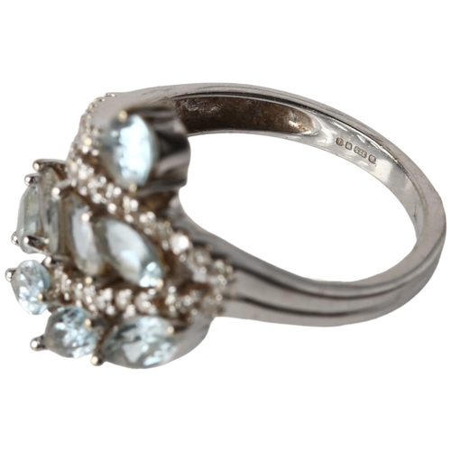 1129 - A modern 9ct white gold blue topaz and diamond crossover ring, maker KRM, London 2008, floral motif ... 