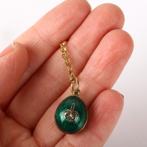 1215 - A late 20th century green enamel egg pendant necklace, on 9ct fine cable link chain, with fleur-de-l... 