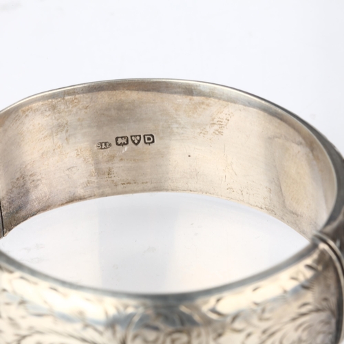 1372 - A mid-20th century silver hinged bangle, maker S&E, Chester 1954, allover engraved foliate decoratio... 