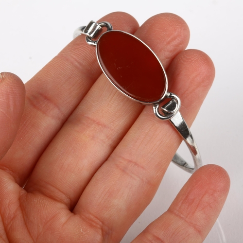 1377 - NIELS ERIK FROM - a Danish modernist sterling silver and carnelian torque bangle, model no. 13, sett... 