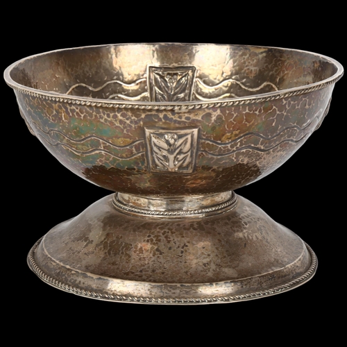 1455 - An Arts and Crafts white metal pedestal bowl, allover planished decoration with relief embossed flor... 