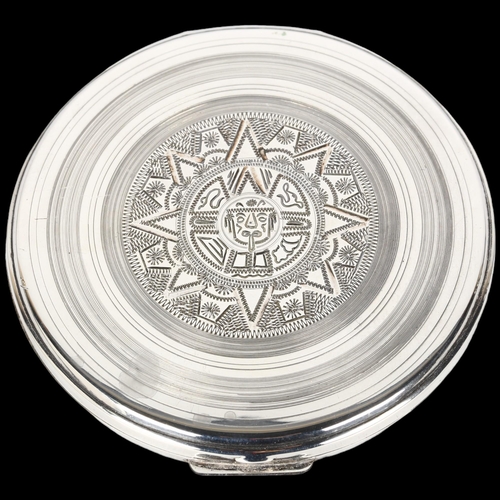 1472 - A large Mexican sterling silver compact, maker CMR, circular form with engraved Aztec decoration, 9c... 