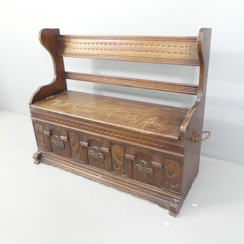 2148 - An early 20th century oak settle, with panelled and carved decoration and lifting seat. 118x97x46cm.