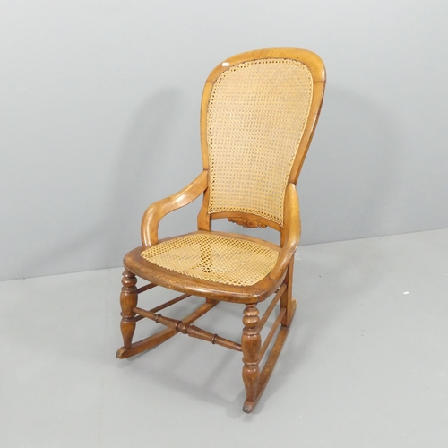 2159 - An early 20th century continental oak rocking chair, with cane back and seat panels. Impressed B to ... 