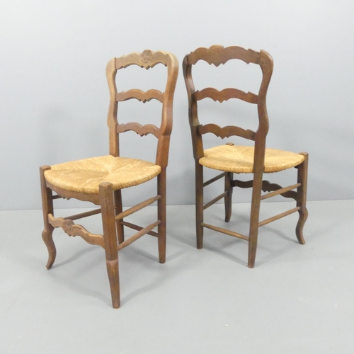 2220 - A set of six French oak rush-seated ladderback dining chairs with carved decoration.