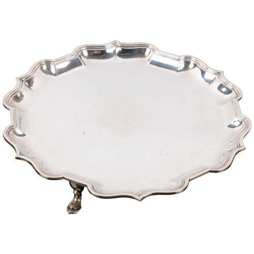 1114 - An Edwardian circular silver salver, CS Harris & Sons Ltd, London 1904, scalloped rim, raised on 3 f... 