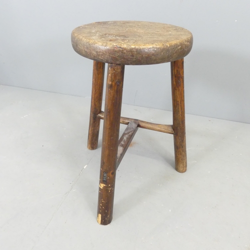 2580 - A rustic elm-seated stool on tripod base. Height 55cm.