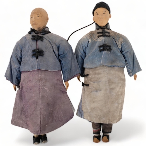 211 - A pair of carved wood Oriental figures, in silk garments, L30cm