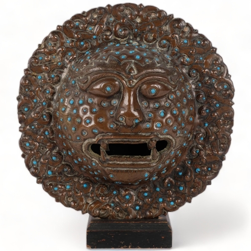 216 - A South East Asian engraved and repousse metal mask, with inset turquoise bosses, diameter 21cm