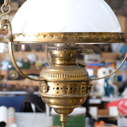 423 - A brass oil lamp style electric light, with milk glass shade and chains, 35cm across