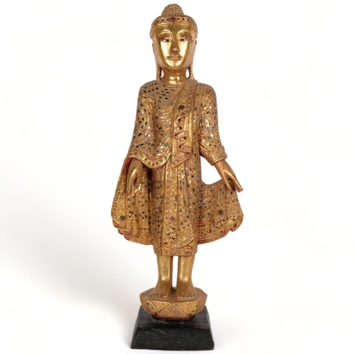 530 - An Oriental carved giltwood figure, with inset mirrored glass fragments, on carved wood plinth, H69c... 