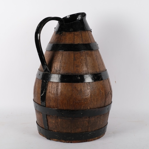 729 - A large coopered oak jug, with metal loop handle and spout, H46cm