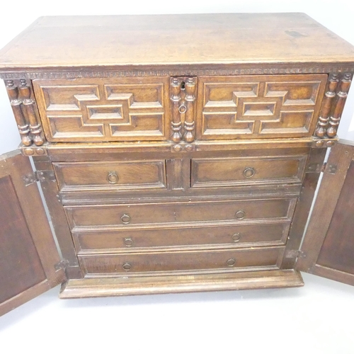 2714 - An early 20th century Jacobean style two-door cabinet, with single drawer to top and two short and t... 