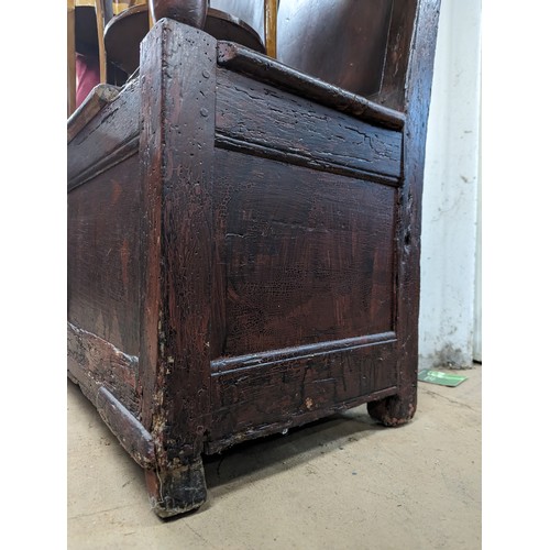 2184 - An antique stained pine settle, with panelled back and lifting seats. Overall 129x118x55cm, seat 116... 