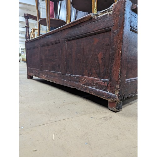 2184 - An antique stained pine settle, with panelled back and lifting seats. Overall 129x118x55cm, seat 116... 