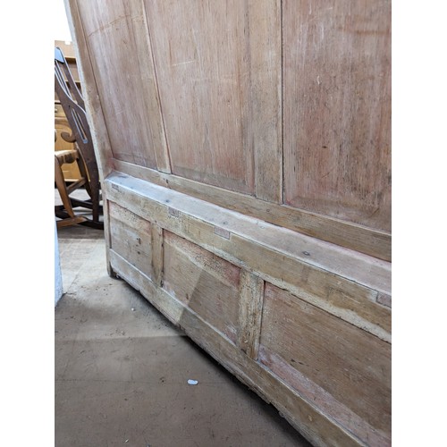 2184 - An antique stained pine settle, with panelled back and lifting seats. Overall 129x118x55cm, seat 116... 