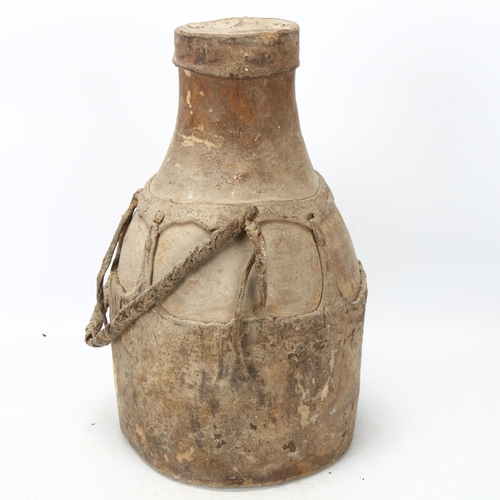 102 - An antique Karamojong Cluster (Uganda) honey pot, a hollow carved wood body and hide cover and strap... 