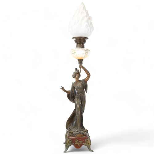 255 - An Art Nouveau oil lamp, supported by a bronze patinated spelter figure of a woman, lustre glass ves... 