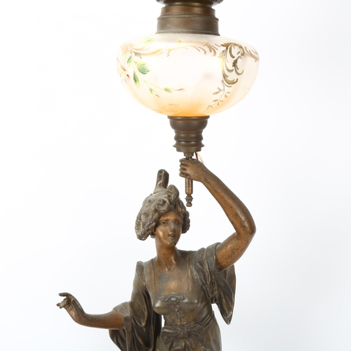 255 - An Art Nouveau oil lamp, supported by a bronze patinated spelter figure of a woman, lustre glass ves... 