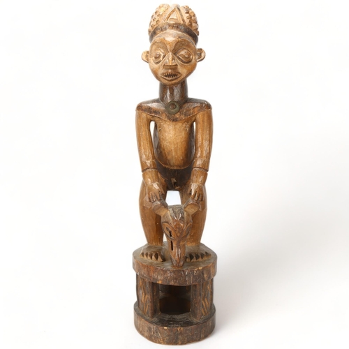 81 - An early/mid 20th century Cameroon carving, of a chief on a stool with a bats head mask, height 65cm