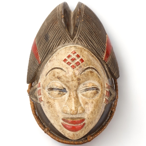 91 - A Punu, Gabon wood carved and painted female mask, with woven raffia border, height 30cm