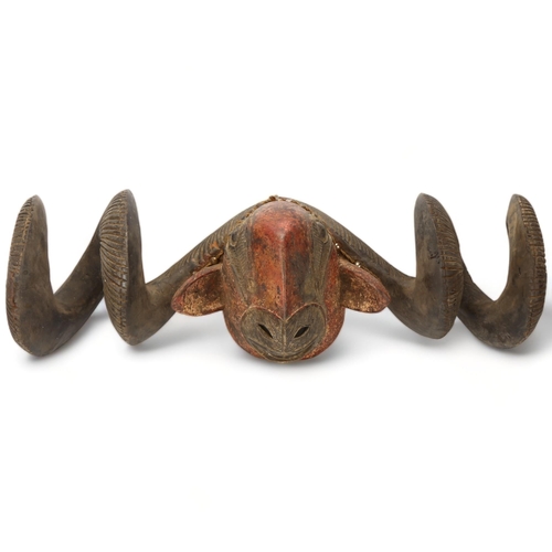 78D - A Baule, Ivory Coast, a large carved wood and painted ram's head mask, length 76cm