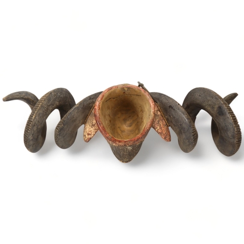 78D - A Baule, Ivory Coast, a large carved wood and painted ram's head mask, length 76cm