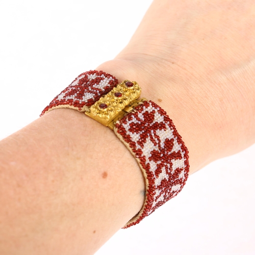 1134 - A Georgian garnet and glass beaded cuff bracelet, circa 1800, the gilt-metal floral clasp suspending... 