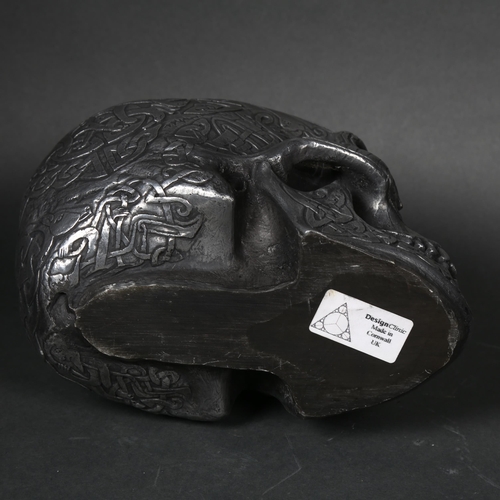 188 - A cast composite sculpture of a human skull, embossed tribal decoration, with figures, birds and ani... 