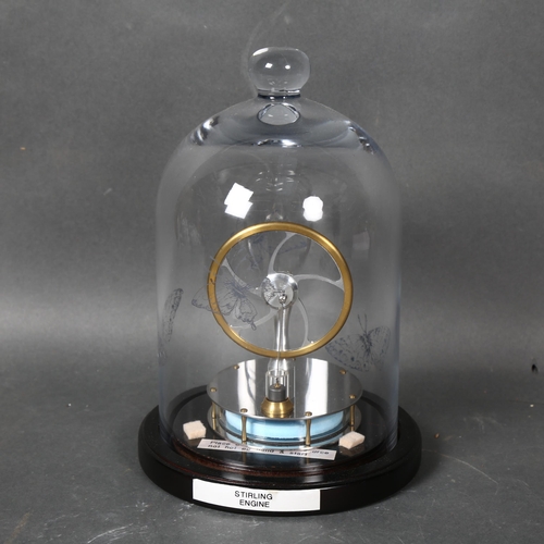 439 - A Stirling engine, mounted under glass dome on stand, height 24cm overall.