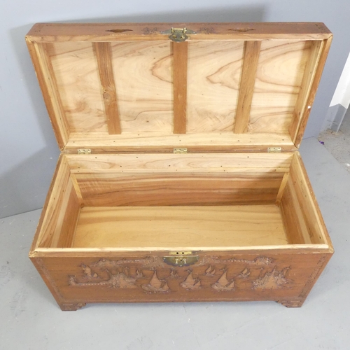 2698 - A Chinese camphorwood chest, with brass lock and relief carved decoration. 105x58x52cm