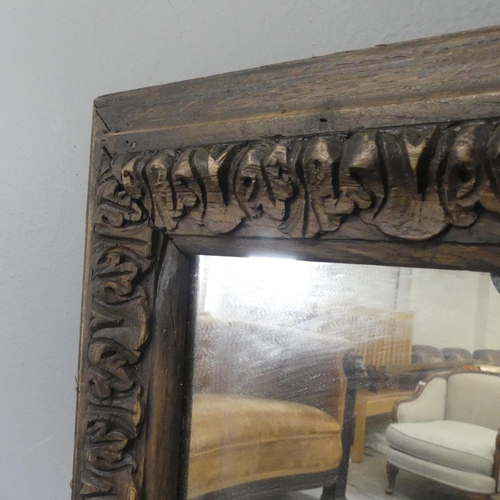 2702 - An antique rectangular oak framed wall mirror with carved decoration. 61x104cm.