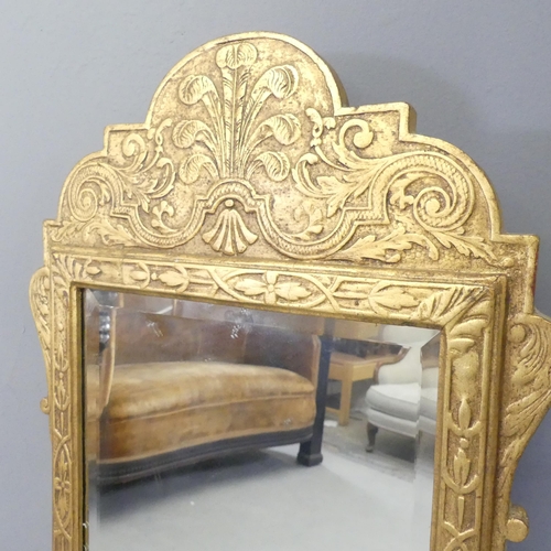 2705 - A continental gilt framed wall mirror with bevel edged glass and carved decoration. 42x107cm.