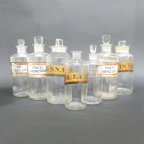 521 - A group of 7 antique clear glass apothecary bottles with original labels and stoppers.