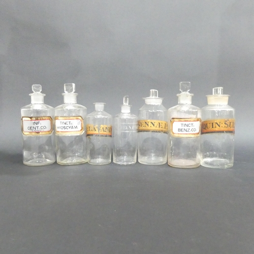 521 - A group of 7 antique clear glass apothecary bottles with original labels and stoppers.