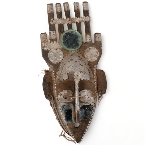 159 - A Mali hardwood mask decorated with press metal and mirrored glass adornments, H40cm