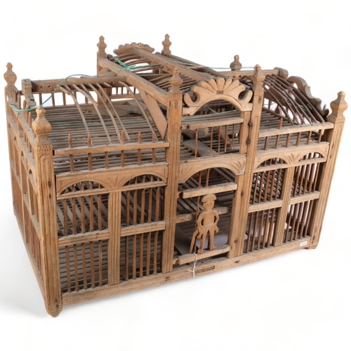 283 - A large palace design wooden hanging bird cage, with figural guard to front door, 76cm x 51cm x 49cm