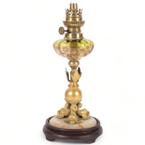 65 - A small gilt-metal oil lamp on an onyx and turned wood base,  with an engraved green glass font, H34... 