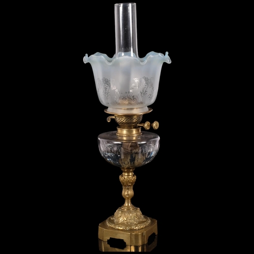 67 - An Antique brass oil lamp, with coloured frilled edge shade and glass font on an embossed brass base... 