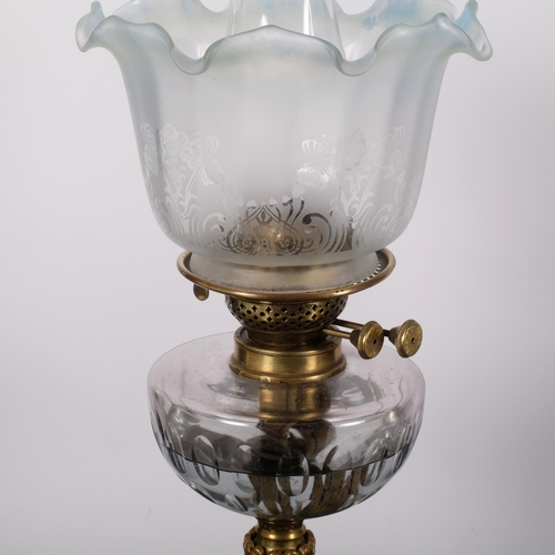 67 - An Antique brass oil lamp, with coloured frilled edge shade and glass font on an embossed brass base... 